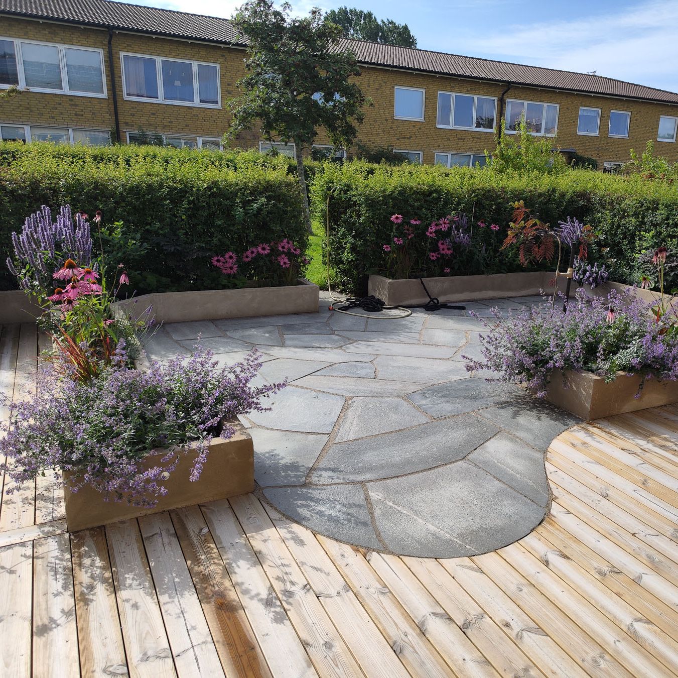 Nyanlagd uteplats med sten och blomlådor.